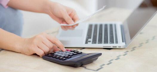 Closeup hands of woman calculating finance household with calculator on desk at home, girl checking...