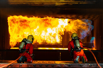 Firefighters teamwork in fire suit on rescue duty using water from hose extinguishing fighting with...
