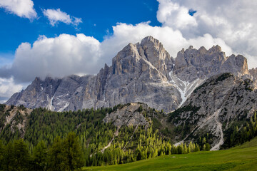 Naklejka premium Dolomites mountains, Alpi Dolomiti beautiful scenic landscape in summer. Italian Alps mountain summits and rocky peaks above green valley alpine scene
