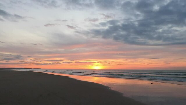 As the sun sets over the ocean, casting a red sky at dusk, the afterglow reflects on the waters surface, creating a peaceful atmosphere in the ecoregion