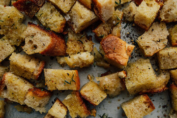cubes of stale sourdough bread with olive oil and herbs on baking sheet to make croutons
