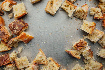 cubes of stale bread with seasoning on baking sheet to make croutons with copy space in middle