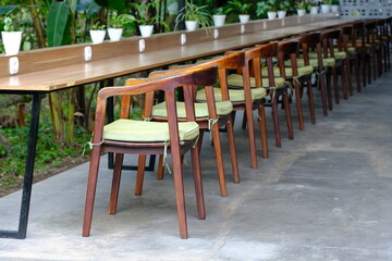 row of wooden chairs and wooden bar table in tropical garden