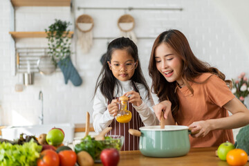 Portrait of enjoy happy love asian family mother with little asian girl daughter child help cooking food healthy eat with fresh vegetable testing smell soup in a pot with spoon.helping mom in kitchen