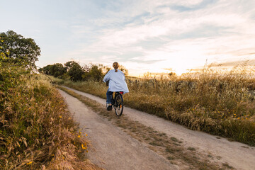 back view of a blonde woman on a bike in a field during sunset
