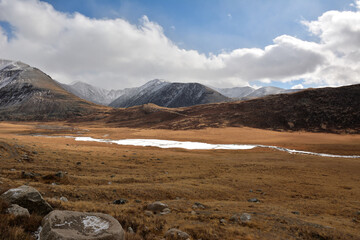 View from the rocky top of the hill to the ice-bound narrow river crossing the autumn valley with...