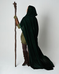 Full length portrait of red haired female model wearing green medieval fantasy costume leather...
