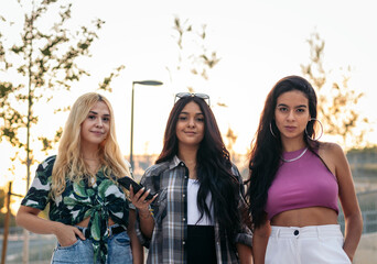 Portrait of three friends standing on the street with smartphone