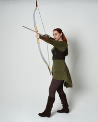 Full length portrait of red haired female model wearing green medieval fantasy costume, leather...