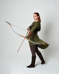 Full length portrait of red haired female model wearing green medieval fantasy costume, leather...
