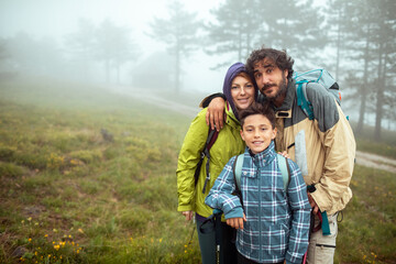 Portrait of a happy family together during a foggy hike in the mountains