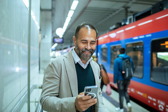 Businessman checking phone while walking through train station