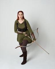 Full length portrait of red haired female model wearing green medieval fantasy costume, leather...
