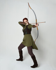 Full length portrait of red haired female model wearing green medieval fantasy costume, leather...