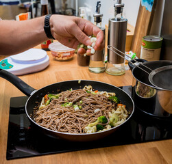 Chef at the kitchen preparing japanese buckwheat pasta with lentils