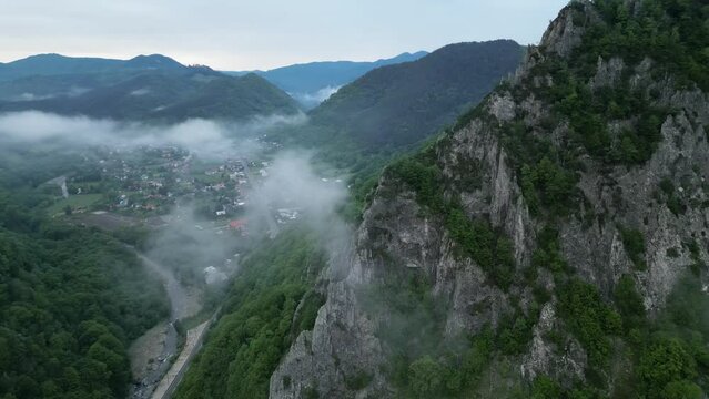 Steep Rock Mountains And Misty Clouds Near Rural Town In Lepsa, Vrancea County, Romania. Aerial Shot