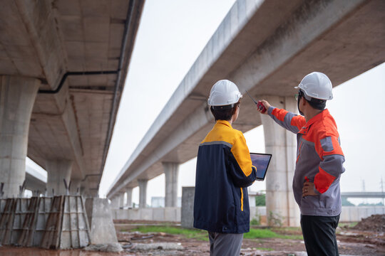 Asian engineering team conducting an inspection at a highway construction site, evaluating the quality of the concrete road and ensuring compliance with standards.