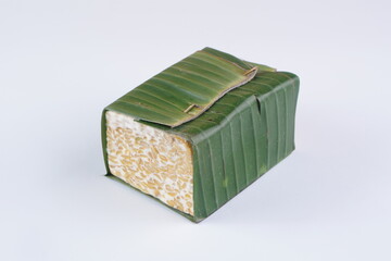 raw tempeh wrapped in Indonesian banana leaves on a white background with studio lighting