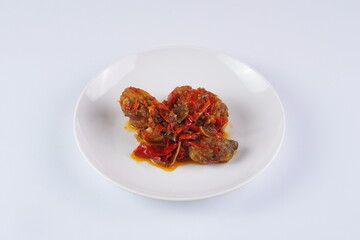 Indonesian typical balado fried chicken on a white plate on a white background with studio lighting