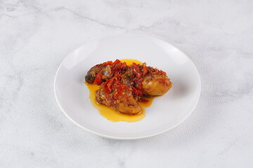 Indonesian typical balado fried chicken on a white plate on a white background with studio lighting