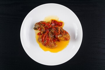 Indonesian typical balado fried chicken on a white plate on a black background with studio lighting