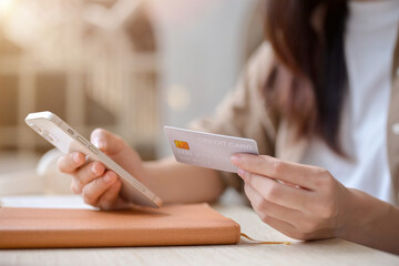 A cropped image of a woman holding her smartphone and a credit card, using a mobile banking app.