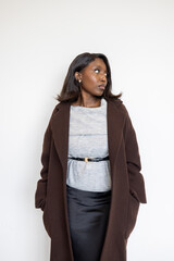 A confident young woman in brown coat, grey top, and black skirt exudes a modern, professional, and stylish aura