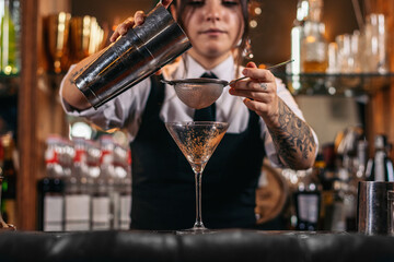 Female bartender preparing a cocktail in a traditional cocktail bar