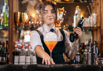 Stylish female bartender preparing a cocktail with a smoke bubble