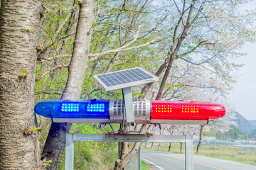 Flashing red and blue traffic light mounted on a aluminum frame, powered by a solar panel in rural...