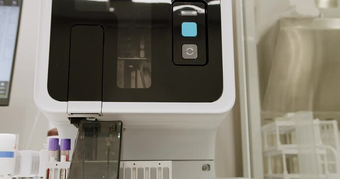 Blood Test Machine with tubes. A blood test with computer equipment. Blood Testing Machine Checks Samples In A Laboratory Room. Automated machine in work process, blood and urine sampleanalysis.