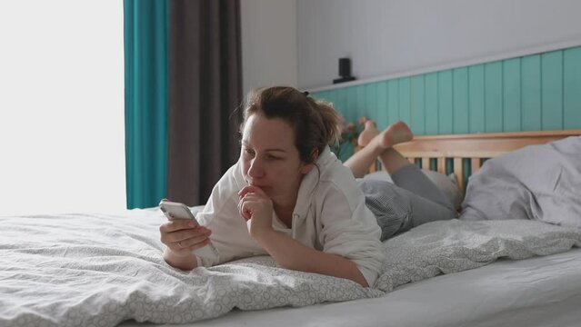 Relaxed Morning Routine of a Young Woman in Her Bedroom Checking Smartphone