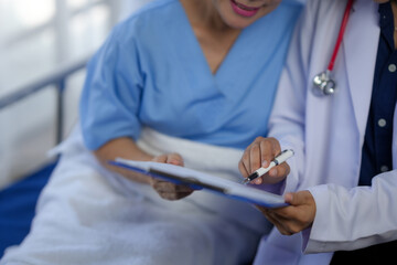Doctor in white coat discussing medical report with patient in hospital bed. Healthcare professional consulting patient in clinical setting.