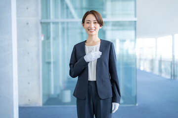 胸に手を当てる白い手袋をつけスーツを着た日本人女性 © ponta1414