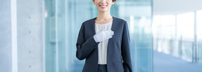 胸に手を当てる白い手袋をつけスーツを着た日本人女性 © ponta1414