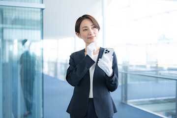 携帯を持つ白い手袋をつけスーツを着た日本人女性