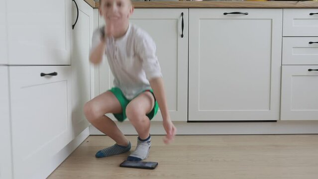 Young Boy Playing a Handheld Game Console in the Kitchen During Afternoon