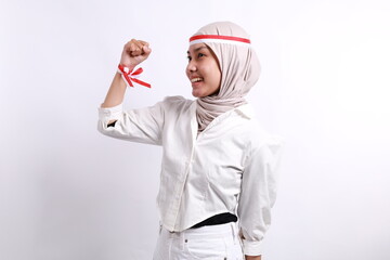 A young Asian muslim woman with a happy successful expression wearing red white flag headband isolated by white background. Indonesia's independence day concept.