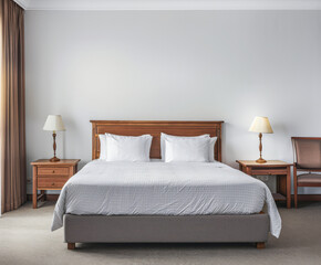 Modern hotel room with elegant bedding and stylish decor. Neutral tones and use of natural light.