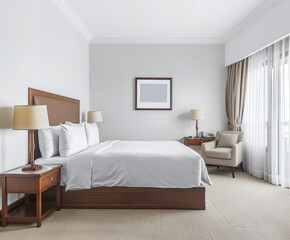 Modern hotel room with elegant bedding and stylish decor. Neutral tones and use of natural light.