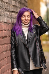 Portrait of a young beautiful girl with purple hair in the autumn city.