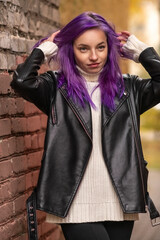 Portrait of a young beautiful girl with purple hair in the autumn city.