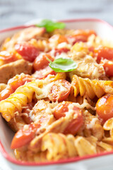 Pasta with chicken breast, cherry tomatoes and fresh basil. Bright wooden background. Close up.