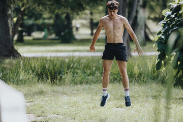 Shirtless young man performing exercises outdoors in a park. Fitness enthusiast enjoying a workout...