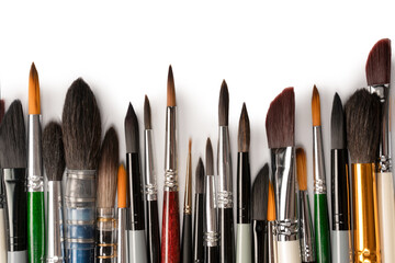 Fototapeta premium Mix of paint brushes in a row isolated on a white background. Top view.