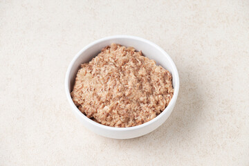 Wet cat food in a white cup on white background.