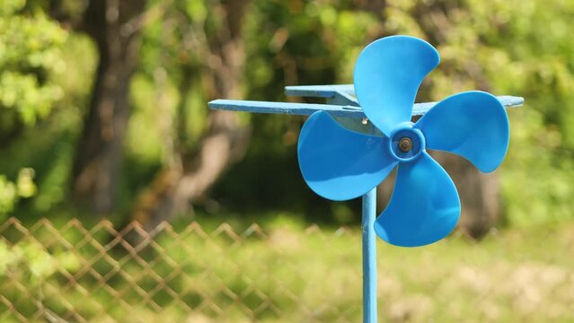 A blue vane weathervane spins in the wind in the summer.