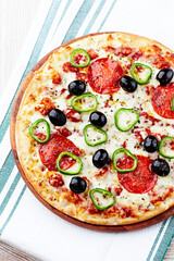 Pizza with salami, jalapeno pepper and black olives. Home made food. Concept for a tasty and hearty meal. Close up.