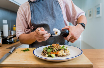 Chef at the kitchen preparing japanese buckwheat pasta with lentils