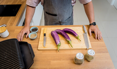 Chef at the kitchen preparing grilled eggplants with garlic